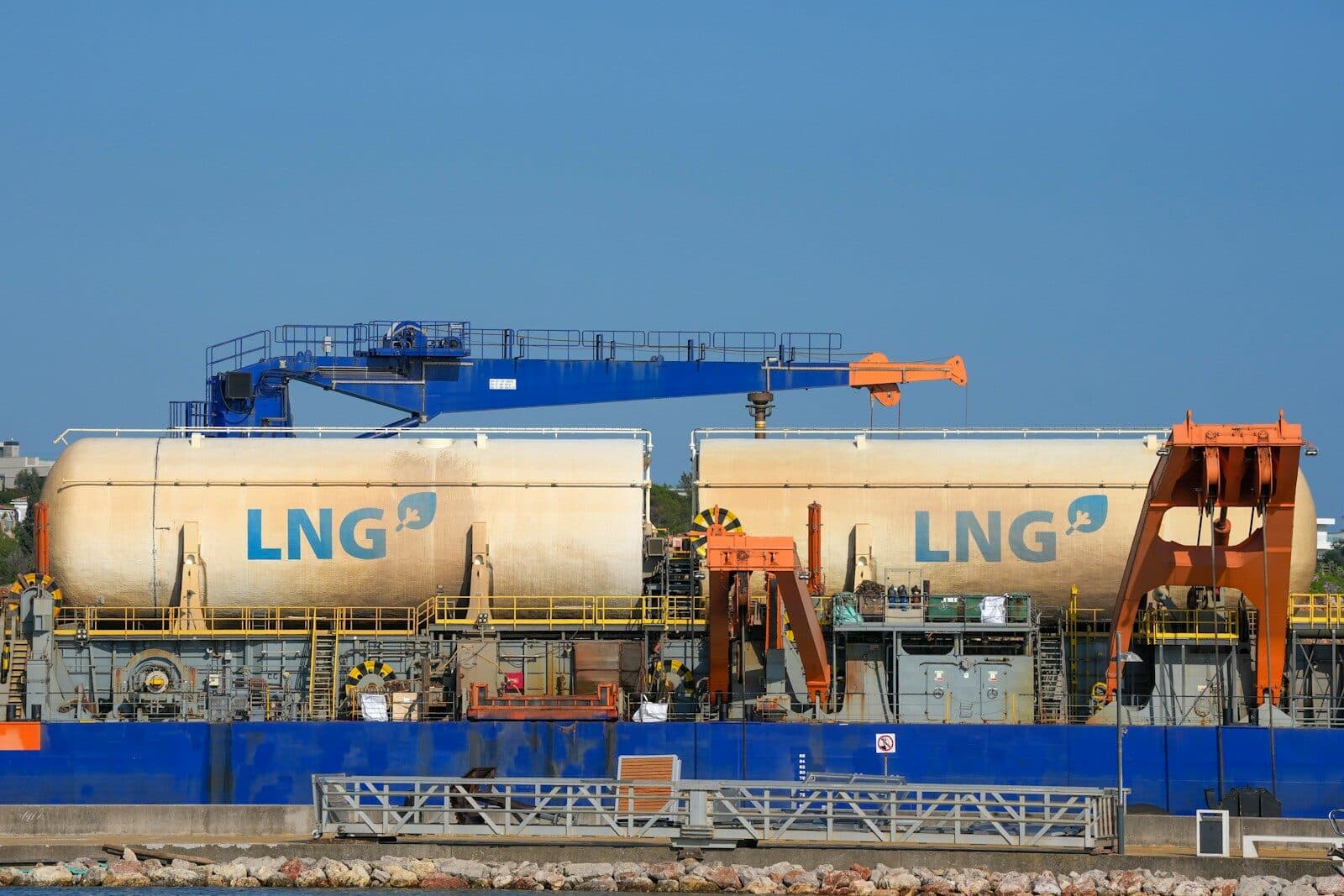 Two large lng tanks on a barge with cranes.