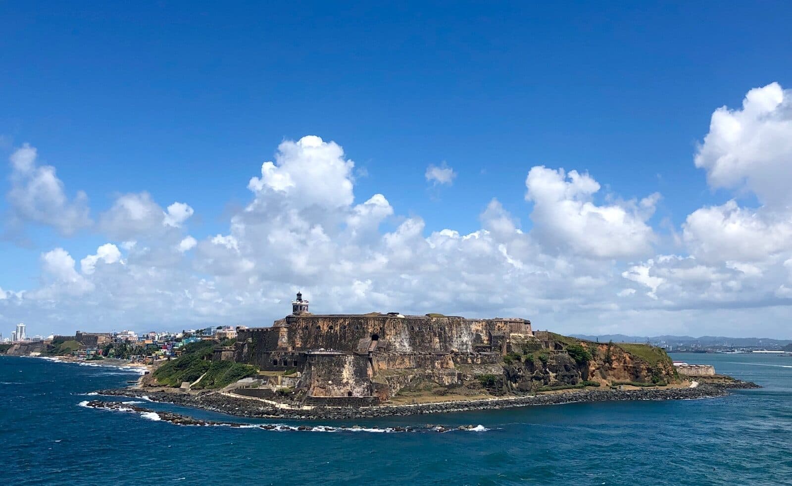 people standing on rock formation near sea under blue sky during daytime