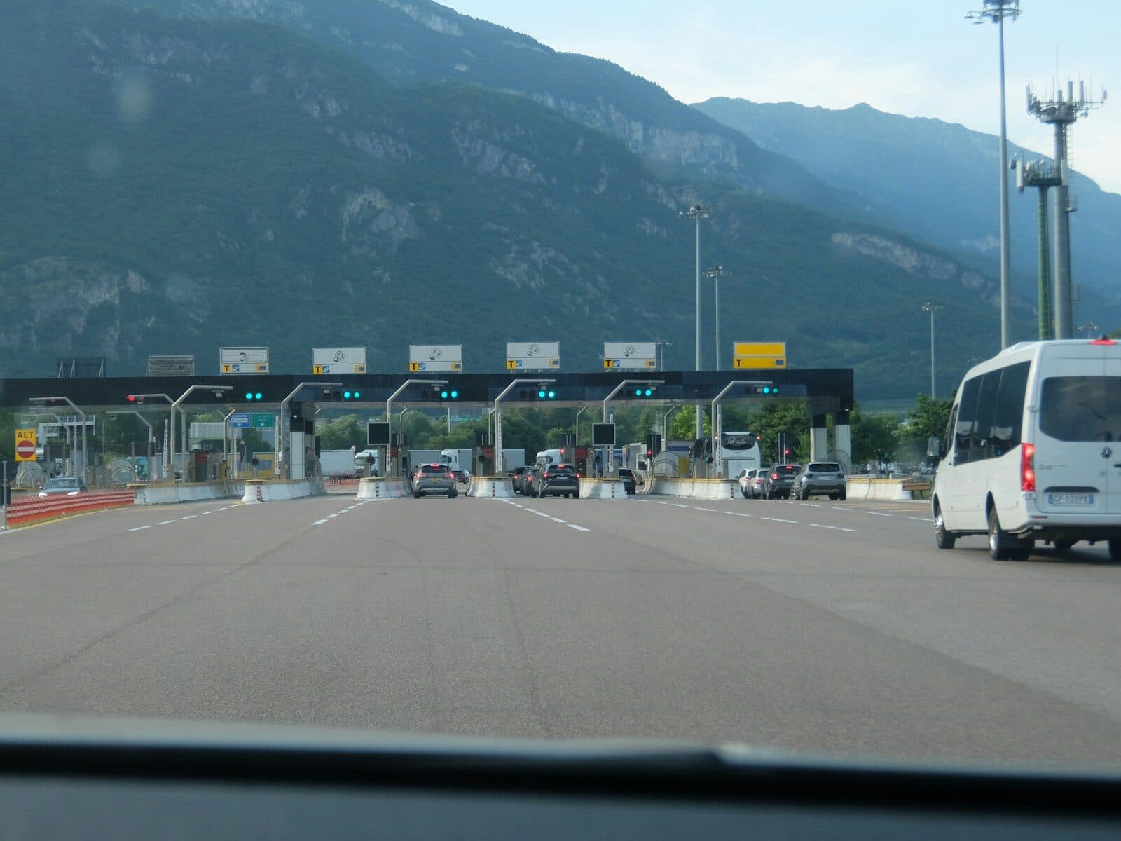Cars approaching a multi-lane toll booth with mountains in background